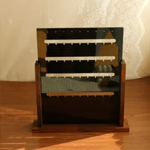 Close-up of wooden earring display stand with dark acrylic slots for jewelry organization