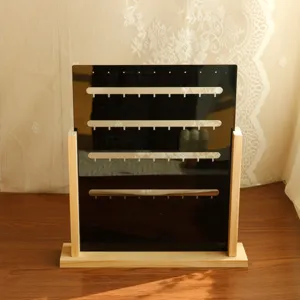 Detailed view of black acrylic earring display stand with wooden base and rows of slots.