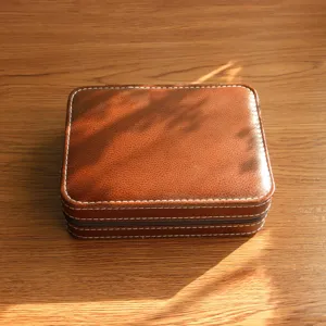 Close-up of a vintage brown leather watch storage box with white contrast stitching.