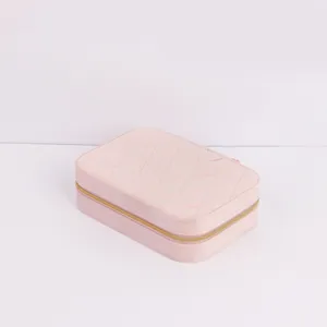 Close-up detail of a pink quilted travel jewelry storage box with golden zipper