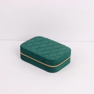 Close-up view of a green quilted velvet travel jewelry box featuring a gold zipper closure