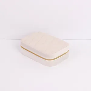 Portable cream quilted jewelry box for travel storage featuring a gold metal zipper