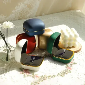Elegant multi-colored matte jewelry ring boxes with gold trim in a sunny lifestyle setting