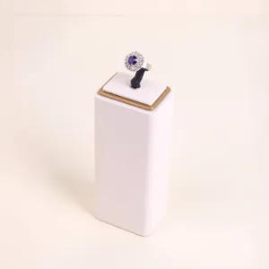 Detail of a creamy white microfiber ring display stand featuring a blue gemstone halo ring