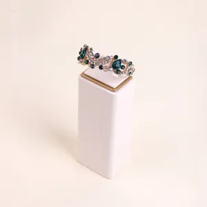 Off-white microfiber jewelry display pedestal stand showing a green crystal bracelet detail