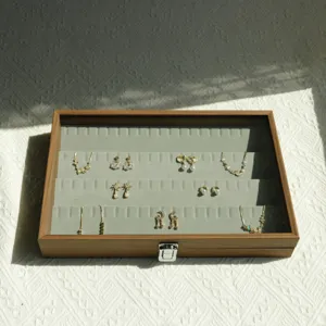Detailed view of walnut grain jewelry box with green velvet slots and various accessories