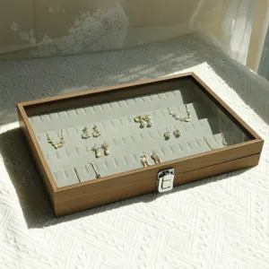 Detail view of walnut wood jewelry box with grey velvet slots and clear glass lid