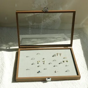 Close-up of walnut wood grain jewelry storage box with clear glass window and rings