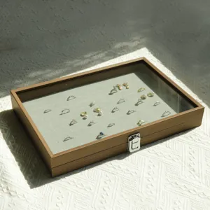 Walnut grain jewelry storage box with glass lid showing multiple rings inside