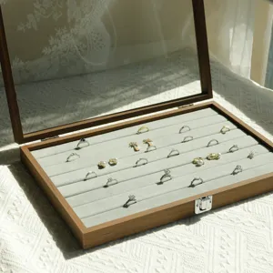 Detail of walnut wood jewelry box featuring grey velvet slots for multiple ring storage.