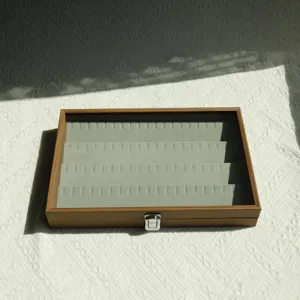 Detailed view of walnut wood jewelry box with grey velvet ring slots and glass lid