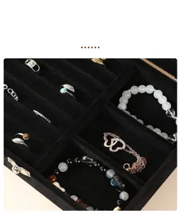 Detailed view of the internal black velvet compartments filled with rings and bracelets