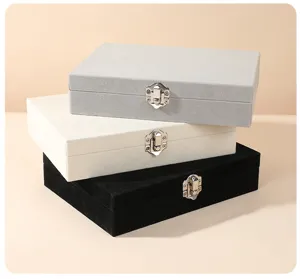 Stack of three premium velvet jewelry boxes in grey, cream, and black with metal buckles.