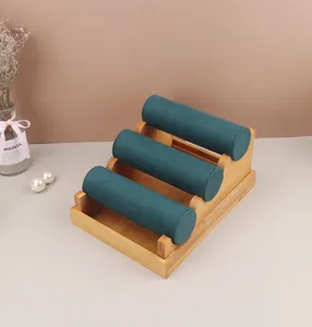 Detailweergave van 3-laags bamboe sieradenstandaard met donkergroene fluwelen rollen.