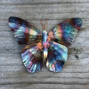 Detailed close-up of a colorful metal butterfly ornament featuring vibrant flamed finish and texture.