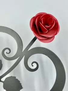 Close-up detail of romantic metal red rose with dark gray scroll heart stand decor for home.