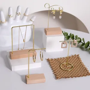 Juego de soportes para joyas con marcos de metal dorado y bases de madera natural.