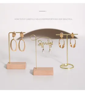 Vista detallada de tres soportes de joyería minimalistas en metal dorado con bases de madera