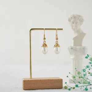 Vista detallada de un elegante expositor de joyas en metal dorado con base de madera maciza