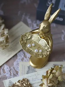 Close-up of vintage pearl earrings on a golden rabbit jewelry display tray