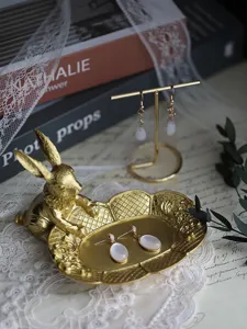 Detailed macro view of a vintage golden rabbit jewelry tray with white earrings
