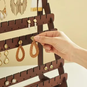 Gros plan d'un présentoir à boucles d'oreilles en bois foncé vintage pour bijoux.