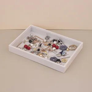 Detailed view of grey soft suede jewelry organizer tray storing various earrings and necklaces