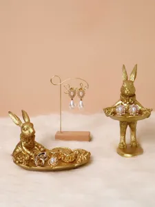 Detailed view of vintage golden rabbit jewelry display props on white faux fur base