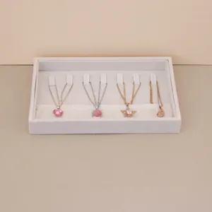 Close-up view of a beige velvet jewelry organizer tray displaying various necklaces