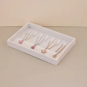 Detail view of a soft suede jewelry tray displaying several elegant pendant necklaces