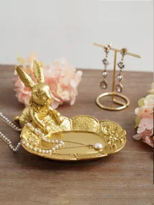 Detailed macro view of vintage golden rabbit jewelry tray with pearl necklace on wood