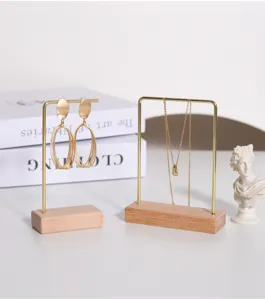 Vista detallada de soportes de joyería de metal dorado y madera con pendientes y collares