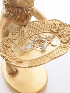 Close-up detail of a vintage golden rabbit display tray holding elegant rings and jewelry