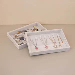 Detailed macro view of two grey velvet jewelry trays holding necklaces and earrings.