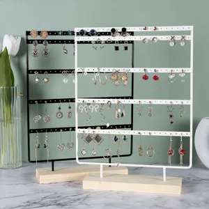 Two multi-layer iron earring display stands with wooden bases on a marble surface