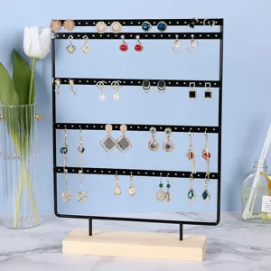 Detail view of black iron earring display stand with wooden base and multiple rows.