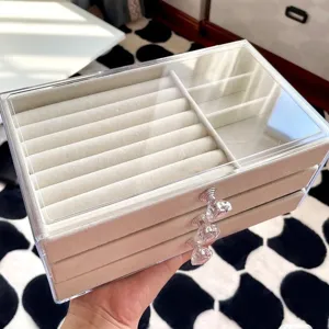 Detailed view of a three-layer velvet jewelry box with crystal handles and clear lid.