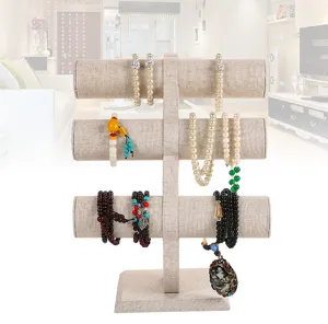 Three-tier linen jewelry display stand for necklaces and bracelets in a home setting