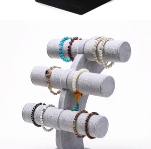Detailed view of a three-tier grey velvet jewelry stand displaying various bracelets