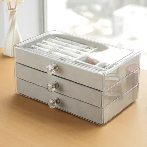 Modern three-layer clear acrylic jewelry box with grey velvet drawers for rings and earrings.