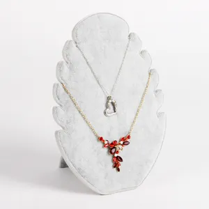 Expositor de joyas de terciopelo gris en forma de hoja con varios collares hermosos