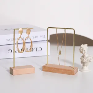 Primer plano de soportes para joyas de madera y metal con pendientes y collar dorados