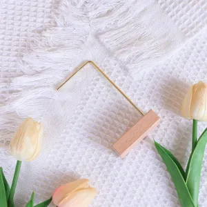 Detalle de un expositor de pendientes minimalista de metal dorado y madera clara.