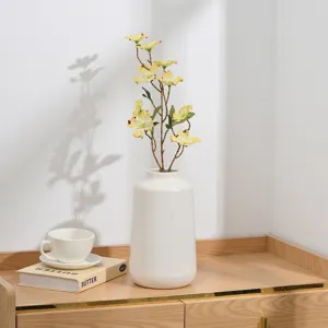 Branche de lilas jaune artificielle dans un vase en céramique blanche pour déco maison photo.