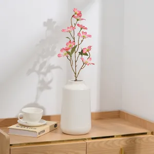 Vue détaillée d'une branche de fleurs de prunier lilas artificiel dans un vase blanc, déco.