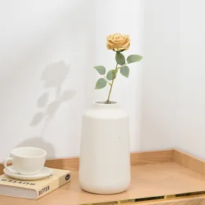 Künstliche kurze Rosenblüte mit weißer Keramikvase für Heim-Desktop-Dekoration.