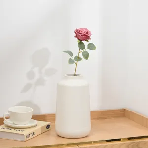 Künstliche rosa Rose in weißer Keramikvase als Tischdekoration und Fotografie Requisite