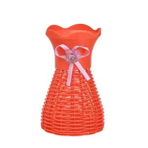Detailaufnahme der roten Kunststoff-Vase mit schöner rosa Schleife und Rosen-Dekoration.
