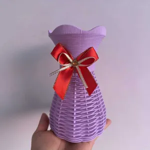 Detaillierte Nahaufnahme der lila Kunststoff geflochtenen Blumenvase mit roter Schleife.