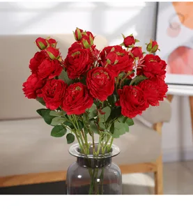 Primo piano di bouquet di fiori artificiali di peonie rose rosse in vaso di vetro.
